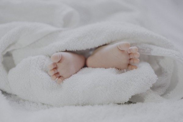 Pieds d'un nourrisson emmitouflé dans un lange